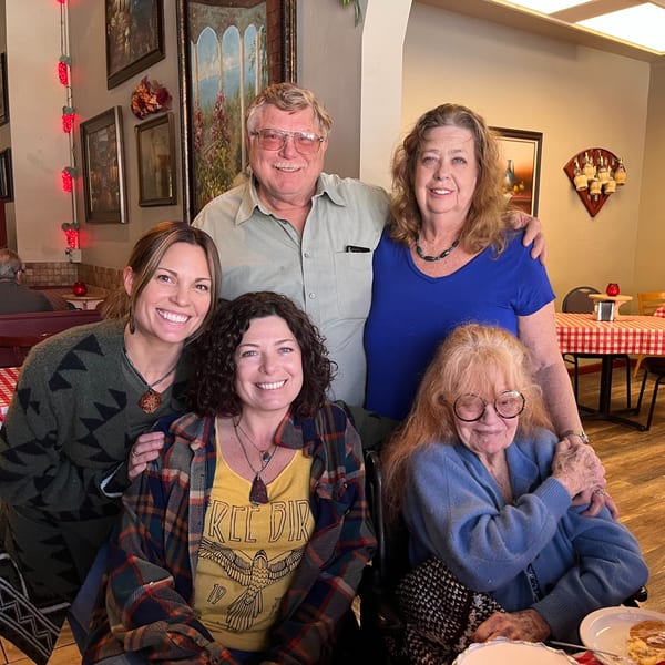 Five smiling people, three women and two men, posing together in an Italian restaurant dining room.