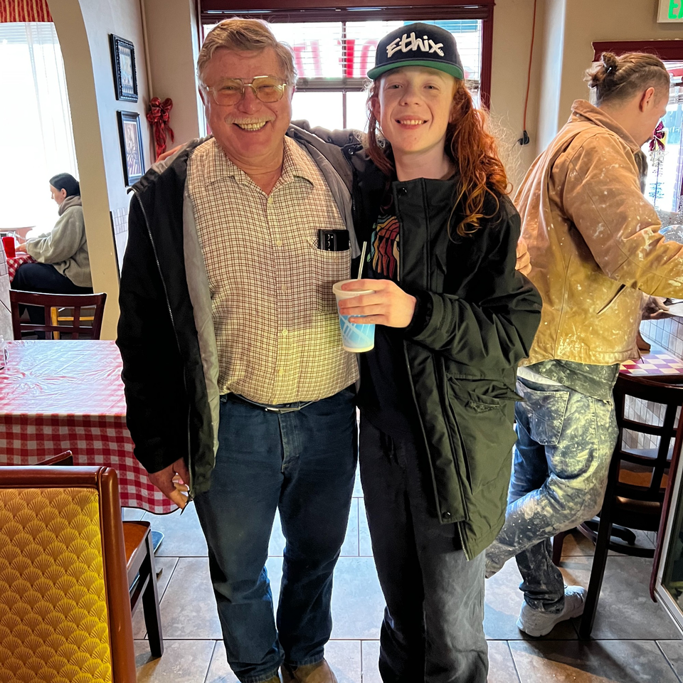 Two men, one older and one younger, smiling at the camera inside the Italian To Go restaurant.