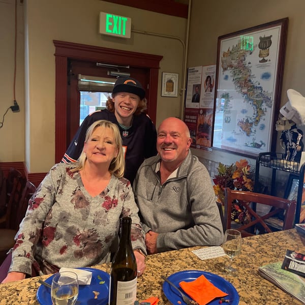 Three smiling people, two adults and one teenager, sitting at a bar in an Italian restaurant.