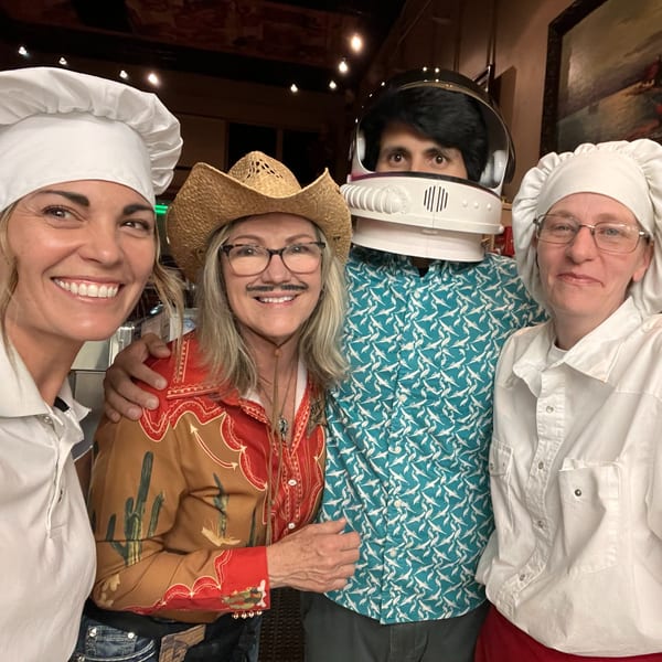 Four people in costumes, including chefs, a cowboy, and an astronaut, smiling at the camera.