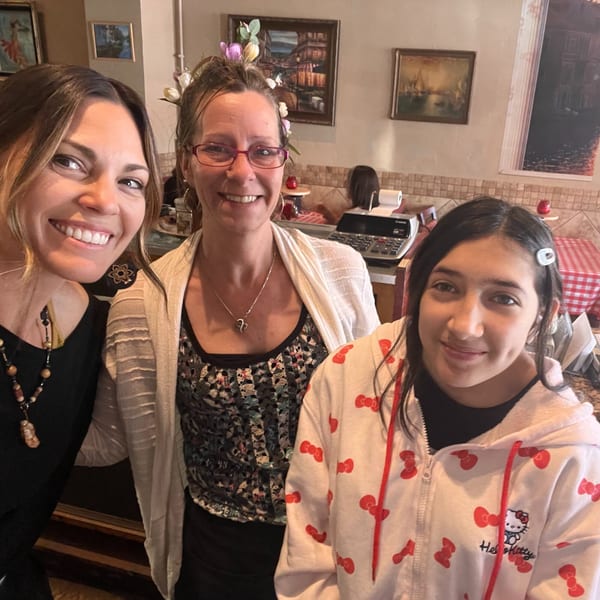 Three smiling women, two adults and one child, pose together inside the Italian To Go restaurant.