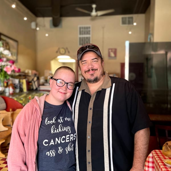 A man and a woman, possibly father and daughter, smiling in an Italian restaurant.